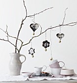 Vintage family photos in pastry cutters and bells hung from branches in china jug