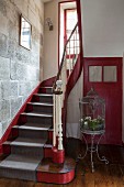 Red and grey stairwell of 18th-century, French country house with stone wall and vintage birdcage