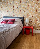 Satin bed linen and floral wallpaper with golden background in elegant bedroom with Oriental ambiance