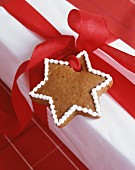 Gingerbread star attached to gift by red ribbon