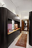 Contemporary, black cupboard installation in open-plan kitchen in traditional interior