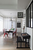 Dining area and decorative station clock above antique school desk in elongated, open-plan interior