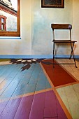 Wooden floor with geometric segments painted in different colours and marbled wall panels