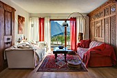 Seating area with red and white sofas, modern arc lamp, Oriental rug and carved wooden wall in prefabricated house