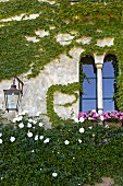 Climber-covered facade with Romanesque window next to wall-mounted lantern (Villa Cimbrone)