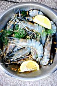Fresh king prawns with lemon wedges and fennel leaves (seen from above)