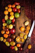 An arrangement of tomatoes with a wooden board and a knife