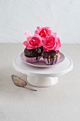 Muffins mit Schokoladenglasur und Rosenblüten dekoriert