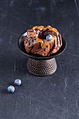 A mini cake with chocolate glaze, caramel sauce and blueberries