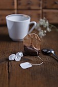 A used tea bag and kluntje rock candy with a tea cup on a wooden table