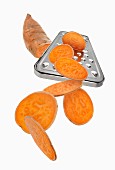 A grater with a sweet potato and sweet potato slices