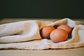 Three brown eggs on a tea towel
