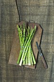 A bunch of green asparagus on a wooden board (seen from above)