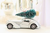 Toy car with Christmas tree on roof against blurred background
