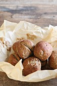 Home-baked, gluten-free buns with flax seed in nest of baking paper
