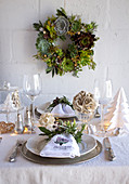 A wreath of succulents above a dining table decorated for Christmas