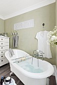 A retro bathtub with a bath rack in a pale green painted country house bathroom