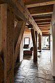 Rustic wooden supporting structure and ceiling beams in loft apartment with slate floor