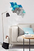 A decorative wall hanging made from homemade tetrahedrons, cut from coloured paper above a sofa