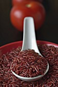 Red rice in a bowl and on a porcelain spoon (close-up)
