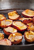 Fried nectarines halves in a pan (close-up)