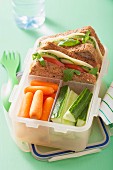 A cheese sandwich and raw vegetables in a lunch box