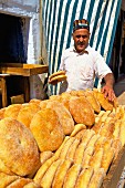 Bäcker mit frischem Fladenbrot an Verkaufsstand (Rabat, Marokko)