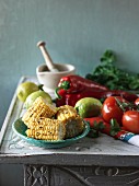 An arrangement featuring grilled corn cobs, tomatoes, peppers, lemons and oil