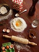 An arrangement of flour, eggs and a rolling pin (seen from above)