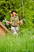 A woman in a meadow with freshly picked vegetables