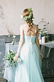 Fairy-tale bride holding bouquet and wearing flower wreath in vintage interior