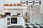 weiße Küchenzeile im Landhausstil mit integriertem Kamin und Kupfertöpfe auf Sims der Abzugshaube