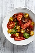 Various different coloured tomato slices on a white plate