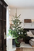 Simply decorated Christmas tree next to cable reel and armchair