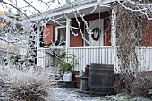 Backsteinhaus mit Veranda im winterlichen Garten mit Raureif