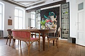 Antique chairs and wooden table in dining room with modern quilt on wall