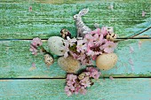 Easter nest with cherry blossom, Easter eggs, quail's eggs and silver Easter bunny on wooden surface