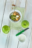 A healthy breakfast: muesli with fresh fruits, nuts and milk, kiwi, apple and melon on a wooden table