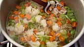 Stirring vegetable soup with noodles in a saucepan