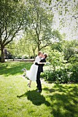 A young bride and groom kissing in a park