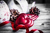 Rote Herzen als Weihnachtsschmuck, Kiefernzapfen und Geschenkbänder