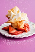 A strudel pastry parcel with icing sugar on strawberry and rhubarb compote