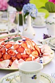 Domed cake decorated with quark and strawberries on table set for afternoon coffee