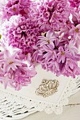 Pink hyacinth flowers, lace doily and rhinestone brooch