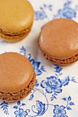 Chocolate and cappuccino macaroons on a blue-and-white floral paper cloth