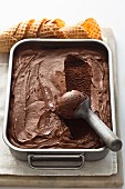 Chocolate ice cream in a container with an ice cream scoop