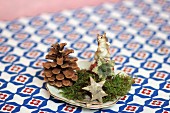 Festive table decoration of pine cone, moss, star and animal ornament