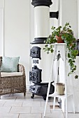 House plant on plant stand next to vintage stove and wicker chair