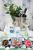 Champagne saucers, ice bucket and food arranged on garden table