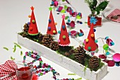 Hand-crafted, festive table decoration with garlands, paper Christmas trees & pine cones